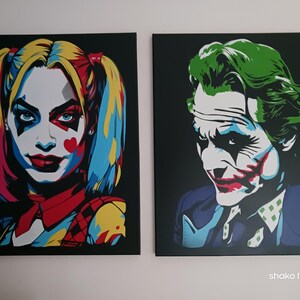 Peut inclure: Deux impressions sur toile de style pop art représentant des personnages de DC Comics. L'une représente Harley Quinn avec des couettes colorées, l'autre le Joker avec des cheveux et du maquillage verts. Les deux sont sur fond noir.