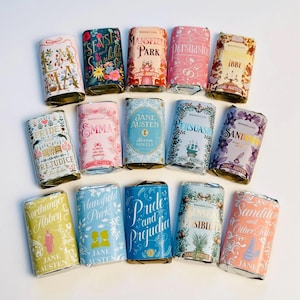 May include: A collection of wrapped chocolate bars, each designed to resemble a classic book cover. The bars feature titles like "Pride and Prejudice" and "Sense and Sensibility" with floral and decorative designs. The bars are arranged on a white surface.