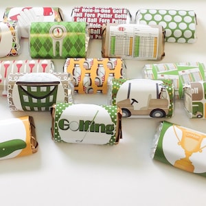 May include: A collection of wrapped candy bars with golf-themed designs. The wrappers feature images of golf carts, golf clubs, scorecards, and the word "Golfing". Colors include green, white, yellow, and red. The candy bars are arranged on a white surface.