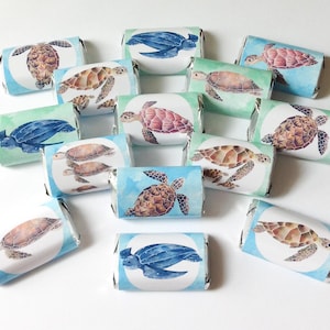May include: An assortment of individually wrapped candies, each featuring a watercolor illustration of a sea turtle. The turtles are depicted in various colors, including blue, brown, and pink, against a backdrop of blue and green watercolor washes.