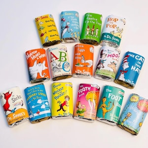 May include: A collection of Dr. Seuss book-themed candies. The colorful wrappers feature iconic characters and titles like "The Cat in the Hat," "Green Eggs and Ham," and "Horton Hears a Who." The candies are arranged on a white surface.