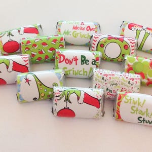 May include: A collection of twelve rectangular candy wrappers featuring festive Grinch-themed designs in red, green, and white. The wrappers display various illustrations of green hands, red ornaments, and text including You're A Mean One Mr. Grinch, Don't Be a Grinch, and Stink! Stank! Stunk!