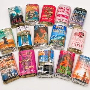 May include: A collection of wrapped books with various titles and authors, including Nora Roberts, Nicholas Sparks, and Danielle Steel. The book covers feature colorful illustrations and text, with titles like "Chasing Fire" and "Whiskey Beach."