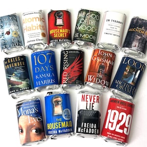 May include: An assortment of miniature book replicas, each wrapped in silver foil. The titles include "Atomic Habits," "The Housemaid's Secret," and "1929." The books feature various colors and designs, creating a visually appealing collection.