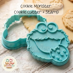Könnte beinhalten: Ein türkisfarbenes Cookie Monster Ausstecher- und Stempelset. Der Ausstecher hat die Form des Kopfes der Figur, mit einem detaillierten Stempel für das Gesicht und einen Keks. Der Text "Cookie Monster Cookie Cutter + STAMP" ist sichtbar.