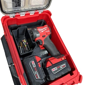 Peut inclure: Une visseuse à chocs Milwaukee Fuel rouge avec une poignée noire, deux batteries M18 Redlithium XC 5.0 et un plateau de rangement en plastique noir contenant divers forets métalliques, le tout dans une mallette de transport rouge ouverte.