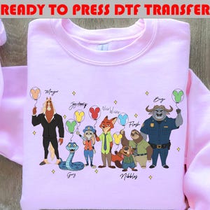 Peut inclure: Un sweat-shirt rose clair avec un motif color&eacute; de personnages de dessins anim&eacute;s, chacun tenant un ballon. Le texte "READY TO PRESS DTF TRANSFER" est en haut. Les personnages incluent Mayor, Joy Happy, Nick Wilde, Flash, Gary, Nibbles et Bogo.