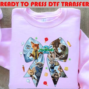 May include: A light pink sweatshirt featuring a large bow design with characters from the movie "Zootopia 2". The bow includes images of a fox, a bunny, and other animals. The text "READY TO PRESS DTF TRANSFER" is at the top.