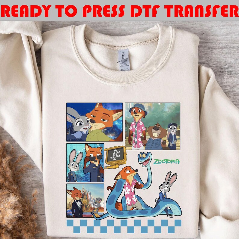 May include: Cream-colored sweatshirt featuring a colorful graphic of characters from the animated movie Zootopia. The graphic includes images of a fox, a rabbit, and other animal characters in various scenes. The words "READY TO PRESS DTF TRANSFER" are printed at the top.