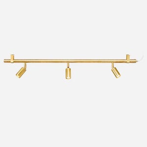 Könnte beinhalten: Eine goldfarbene Schienenbeleuchtung mit drei verstellbaren Strahlern. Die Leuchte ist horizontal montiert und hat ein klares, modernes Design. Die Strahler sind zylindrisch und können zur Lichtlenkung angewinkelt werden.