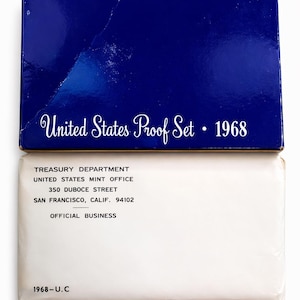 May include: A blue box labeled "United States Proof Set • 1968" sits atop a white envelope. The envelope is printed with "Treasury Department, United States Mint Office, 350 Duboce Street, San Francisco, Calif. 94102, Official Business, 1968-U.C."