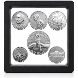 May include: A black square floating display frame containing five silver-toned coins. The coins feature various designs including George Washington, a ship, a torch held by two hands with the text KNOWLEDGE IS THE CHILD OF LIBERTY, a dime, and Monticello.