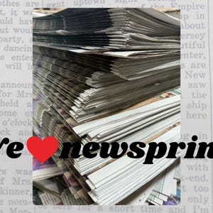 May include: A stack of newsprint pages with the text "We ❤️ newsprint!" in black and red. The pages are stacked high, with visible text and images from the newspaper.