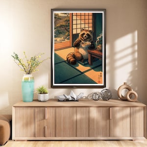 Puede incluir: Impresión artística enmarcada que representa a un mapache comiendo en un entorno japonés tradicional. El mapache es marrón y blanco, sentado sobre una estera de tatami. La escena incluye una tetera, una ventana y texto japonés.