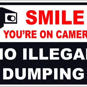 May include: Black and white sign with red text that reads "SMILE YOU'RE ON CAMERA NO ILLEGAL DUMPING". The sign features a black and white silhouette of a security camera.