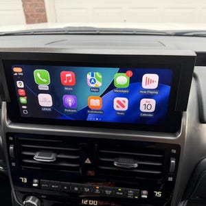 May include: A black car dashboard with a digital display showing various app icons, including Phone, Music, Maps, and Messages. The screen is mounted within a black frame. The temperature is displayed as 73 degrees Fahrenheit.