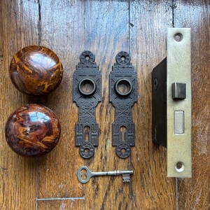Juego de herrajes para puertas: pomos de puerta de porcelana marmolada antigua y placas traseras de hierro fundido.