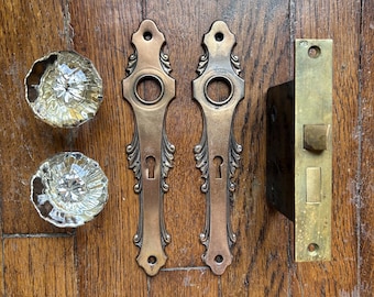 Herrajes antiguos de estilo Art Nouveau para puertas, con pomos de cristal estriado y placas de latón.