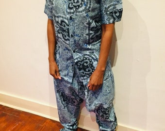 Puede incluir: Un conjunto de camisa y pantalón con estampado azul y negro. La camisa tiene cuello y mangas cortas. El pantalón es holgado y tiene pierna ancha.
