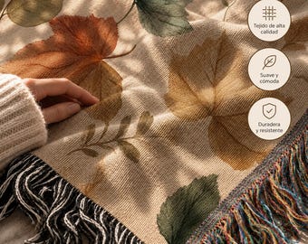 May include: A beige woven throw blanket featuring a pattern of autumn leaves in shades of green, orange, and brown. The blanket has a textured knit construction and is finished with decorative fringe along the edge in black, white, and multicolored threads.