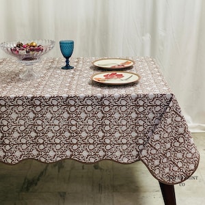 Authentic Indian hand block print cotton tablecloth in rich Mud Brown tones featuring floral patterns and matching piping border. This reusable dining table linen is beautifully styled with layered plates, candles, and greenery to create an inviting boho farmhouse atmosphere for weddings, dinner parties, brunch gatherings, seasonal décor, and elegant home entertaining.