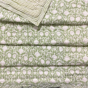 May include: A quilted blanket featuring a sage green background with a repeating white floral pattern and a folded corner revealing a white and sage green striped underside. The text Floral Print Co is printed in the bottom right corner.