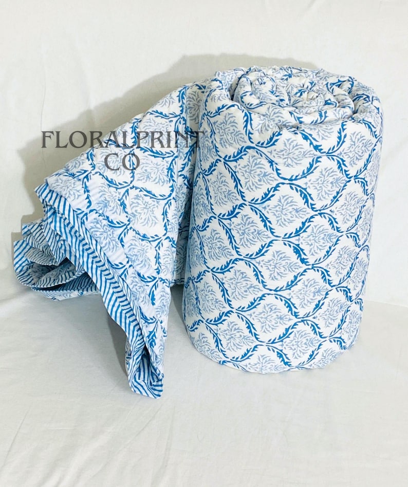 Reversible floral quilt made from soft cotton with traditional block print artistry. Designed as a lightweight comforter blanket that works beautifully in all seasons. Use it on a bed, sofa, reading chair, or daybed for cozy comfort and elegant style. Handmade details and breathable fabric make this quilt both practical and decorative for modern or boho home interiors.