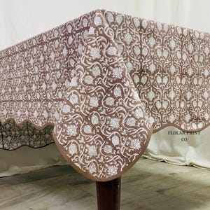 Decorative Mud Brown rectangular tablecloth with floral hand block print and coordinated piping detail styled for farmhouse wedding décor and everyday dining. Crafted from breathable 100% cotton, this handmade reusable table cover blends traditional Indian craftsmanship with modern boho elegance, making it perfect for dining rooms, parties, holiday hosting, and special gatherings.
