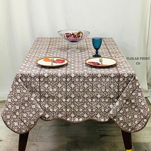 Beautiful Mud Brown floral block print tablecloth made from 100% pure cotton featuring traditional Indian hand block printing artistry. The rectangular dining table cover is styled with ceramic dinnerware, candles, and natural décor accents to create a welcoming boho farmhouse tablescape ideal for holiday dinners, wedding décor, brunch parties, and elegant indoor dining spaces with a rustic vintage touch.