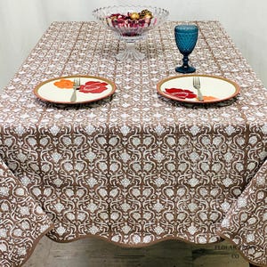 Elegant Mud Brown hand block printed tablecloth featuring intricate floral motifs and refined piping detail photographed in natural lighting. The soft cotton dining table cover enhances rustic farmhouse interiors, cozy dining rooms, and boho-style wedding tables while adding warmth and sophistication to everyday meals, festive celebrations, and special event table settings.