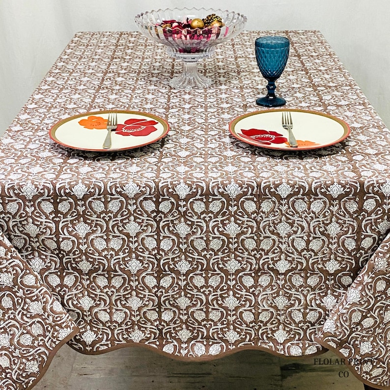 Elegant Mud Brown hand block printed tablecloth featuring intricate floral motifs and refined piping detail photographed in natural lighting. The soft cotton dining table cover enhances rustic farmhouse interiors, cozy dining rooms, and boho-style wedding tables while adding warmth and sophistication to everyday meals, festive celebrations, and special event table settings.
