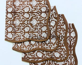 May include: Four brown and white floral patterned placemats with scalloped edges. The placemats feature a repeating white floral design on a brown background, with a brown border.