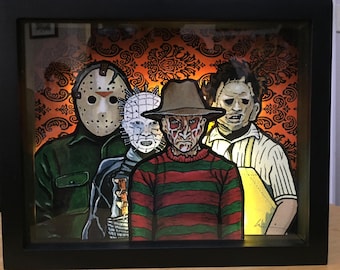 May include: A framed illustration of five horror movie characters. The characters are Jason Voorhees, Freddy Krueger, Pinhead, Leatherface, and Michael Myers. The background is a dark orange and black damask pattern.