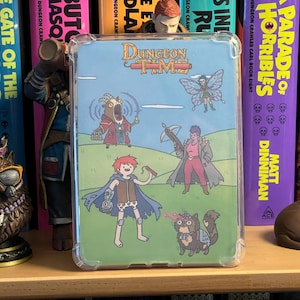 May include: A clear protective case for a handheld device featuring a colorful cartoon illustration titled Dungeon Time. The artwork depicts a group of fantasy characters, including a goat-like creature, a winged figure, a warrior, and a cat.