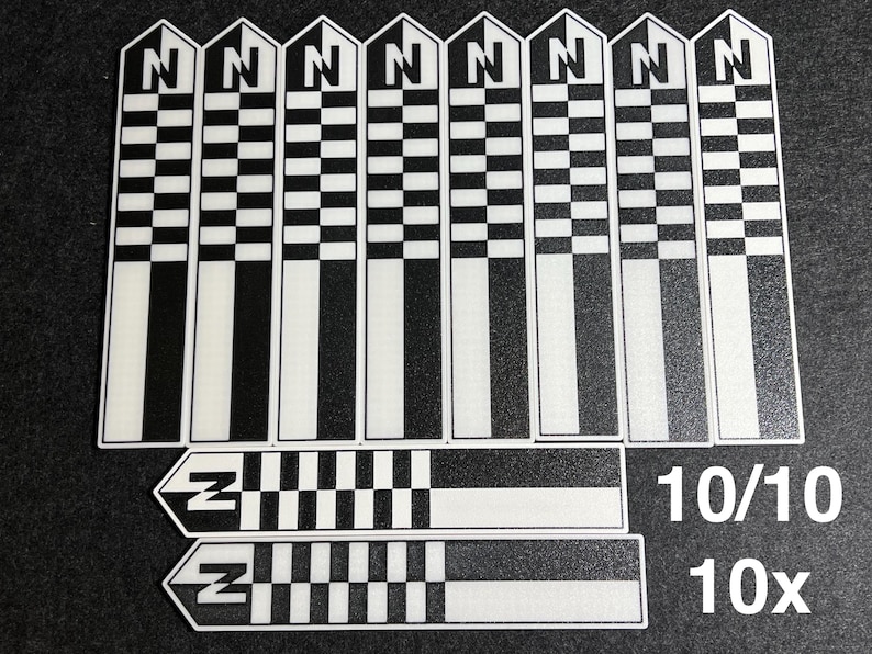K&ouml;nnte beinhalten: Eine Sammlung schwarz-wei&szlig; karierter Aufkleber mit dem Buchstaben "N" oben. Die rechteckigen Aufkleber haben ein Schachbrettmuster und einen wei&szlig;en Streifen. Zwei zus&auml;tzliche Aufkleber mit dem Buchstaben "Z" sind ebenfalls vorhanden, zusammen mit dem Text "10/10" und "10x".