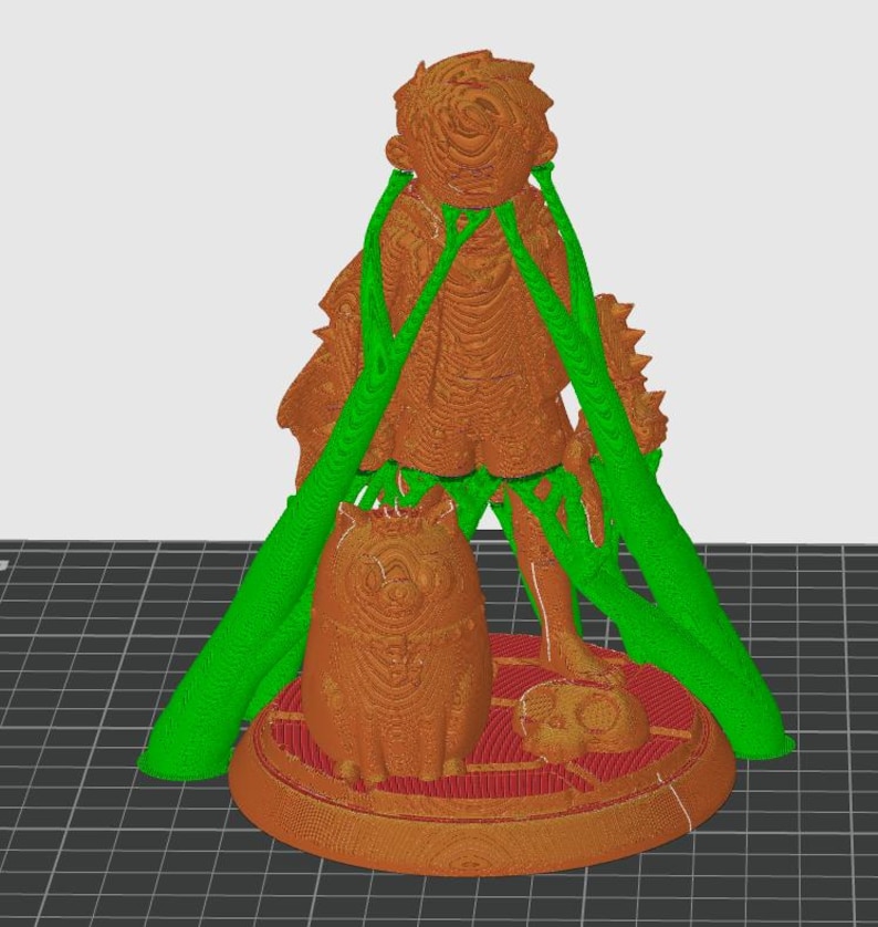 Op de afbeelding: Een 3D-geprinte figuur met een figuur met een vloeiende jurk, een kat en een kleine schedel. De figuur is bruin met groene ondersteuningsstructuren. De basis is rood en cirkelvormig.