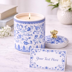 May include: A burning candle in a white and blue floral patterned ceramic container with a lid. A matching card with the text "Your Text Here" is in front of the candle. The candle and card are on a marble surface.