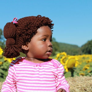 Another adorable toddler in a sunflower field is wearing the dark brunette hat, which is a dark brown color.