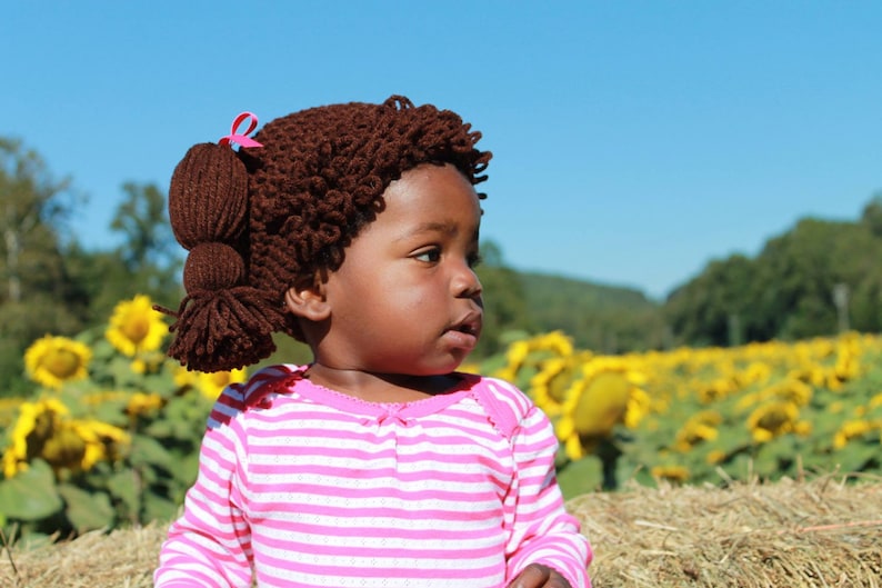Another adorable toddler in a sunflower field is wearing the dark brunette hat, which is a dark brown color.