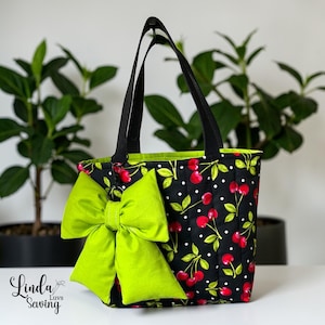 May include: Black tote bag with a cherry print and a large lime green bow. The bag has black handles and a lime green interior. The text "Linda Luvs Sewing" is in the lower left corner.