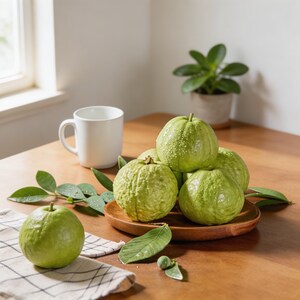 May include: A collection of fresh, light green guavas with textured skin, some piled on a round wooden plate and one resting on a white and black checkered cloth. A plain white ceramic mug sits nearby on a wooden surface.