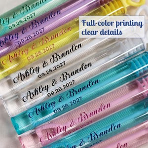 May include: A collection of clear plastic bubble wand tubes featuring various colored wands inside. Each tube is printed with the text Ashley & Brandon 09.26.2027 in different colors and fonts. A white box with the text Full-color printing clear details is visible.