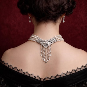 May include: A multi-strand pearl choker necklace featuring a central silver-toned metal ornament encrusted with clear crystals and a dangling fringe of teardrop-shaped crystals. Matching crystal drop earrings are worn on the earlobes.