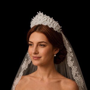 May include: A white beaded tiara featuring intricate swirling patterns and small pearls, paired with a sheer white veil that has a delicate lace trim along the edges. The tiara sits atop the head, while the veil drapes down the sides.
