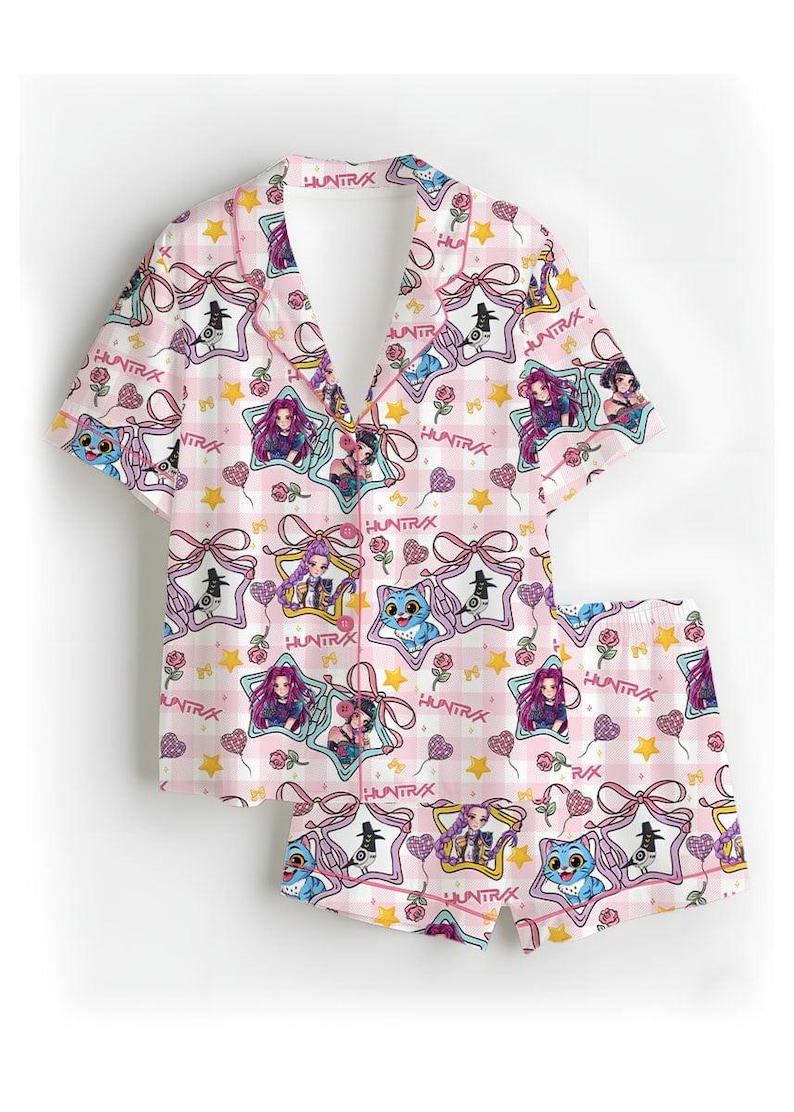 May include: Pink pajama set with a repeating pattern of cartoon characters, stars, and bows. The set includes a short-sleeved button-up shirt and matching shorts. The text "HUNTRAX" is visible throughout the design.