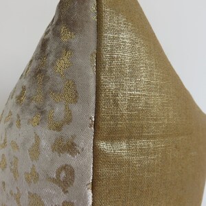 Puede incluir: Un coj&iacute;n decorativo con un dise&ntilde;o de dos tonos. Un lado presenta una tela de terciopelo gris claro y suave con estampado de leopardo dorado. El otro lado es una tela dorada texturizada. El coj&iacute;n es un art&iacute;culo de decoraci&oacute;n del hogar neutro.