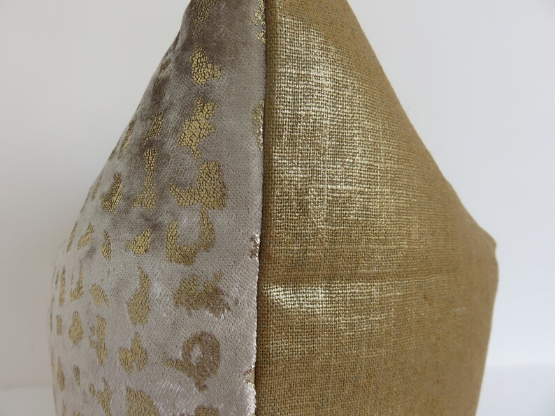 Puede incluir: Un coj&iacute;n decorativo con un dise&ntilde;o de dos tonos. Un lado presenta una tela de terciopelo gris claro y suave con estampado de leopardo dorado. El otro lado es una tela dorada texturizada. El coj&iacute;n es un art&iacute;culo de decoraci&oacute;n del hogar neutro.