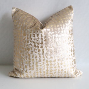 Puede incluir: Un coj&iacute;n decorativo cuadrado con una superficie suave y texturizada. El coj&iacute;n presenta un fondo crema con un patr&oacute;n dorado punteado. El coj&iacute;n est&aacute; dise&ntilde;ado para la decoraci&oacute;n del hogar y a&ntilde;ade un toque de elegancia a cualquier habitaci&oacute;n.