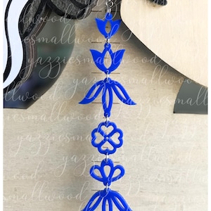 May include: A long, dangling blue earring with a floral design. The earring features multiple connected shapes, including tulip-like forms and a four-leaf clover. The earring is suspended from a silver hook.
