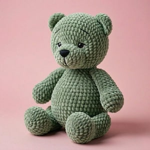 Peut inclure: Un ours en peluche au crochet vert sauge avec un nez noir et des yeux brod&eacute;s. L'ours en peluche est assis sur un fond rose. L'ours a un aspect textur&eacute; et doux. Un jouet c&acirc;lin fait &agrave; la main.